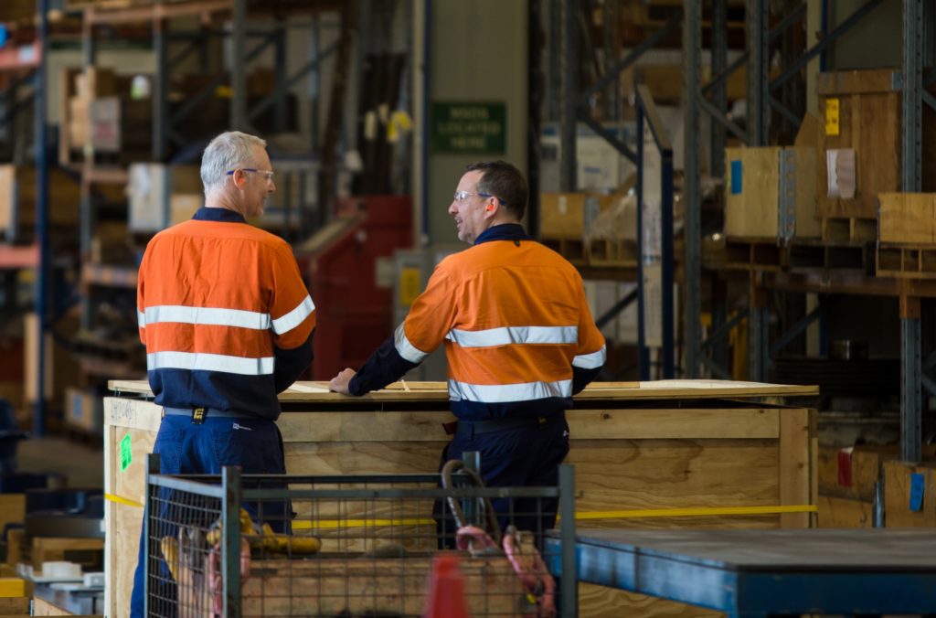 two men in uniform chatting in warehouse