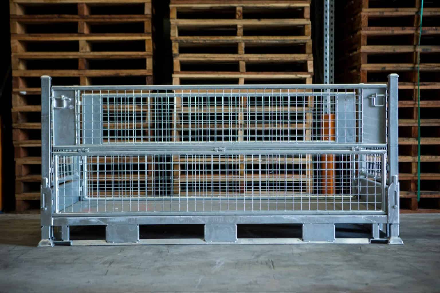 steel cage in front of stacks of hardwood pallets