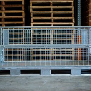 steel cage in front of stacks of hardwood pallets