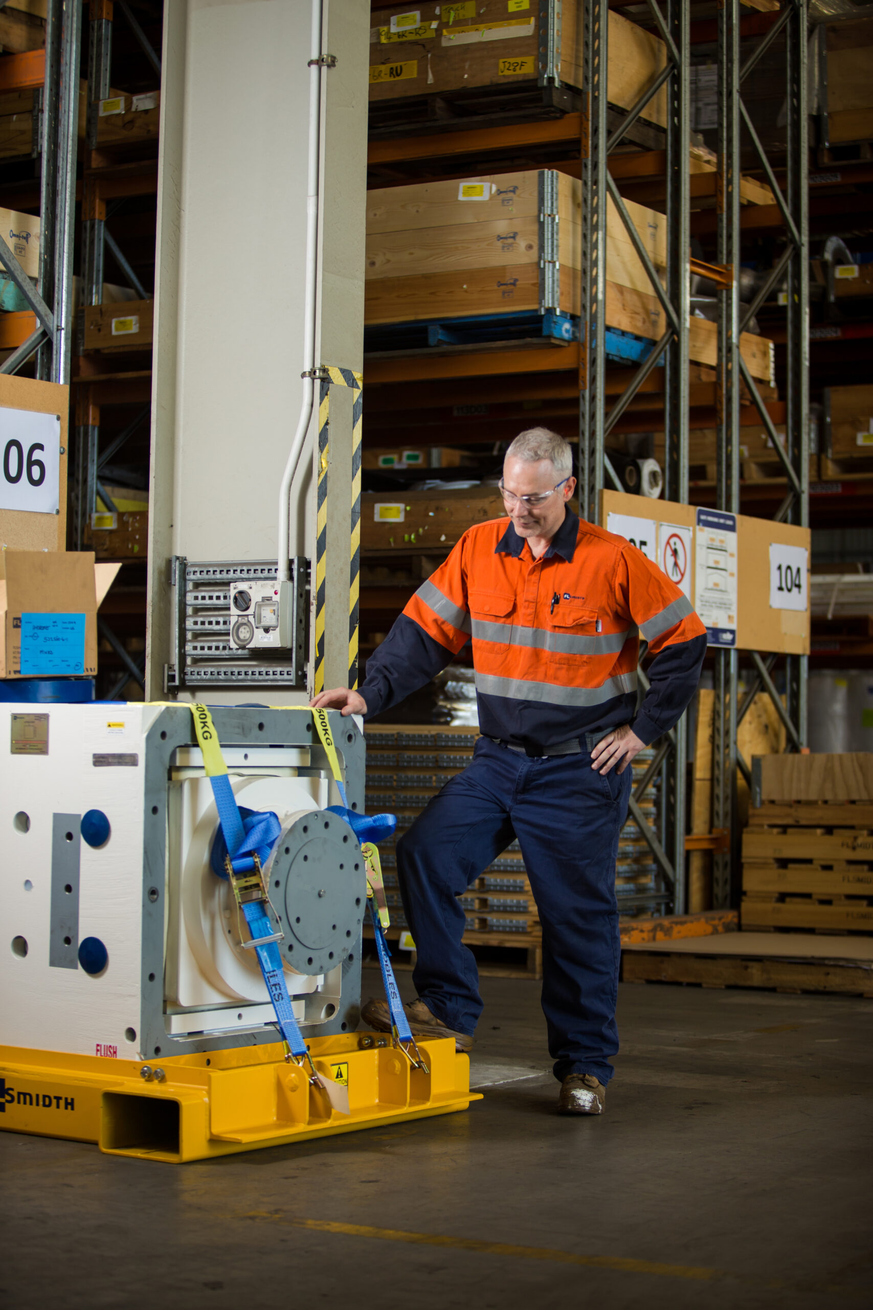 man in hivis securing a component in a warehouse