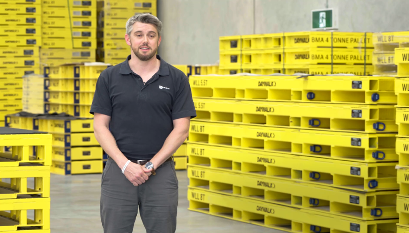 man in warehouse standing in front of steel pallets